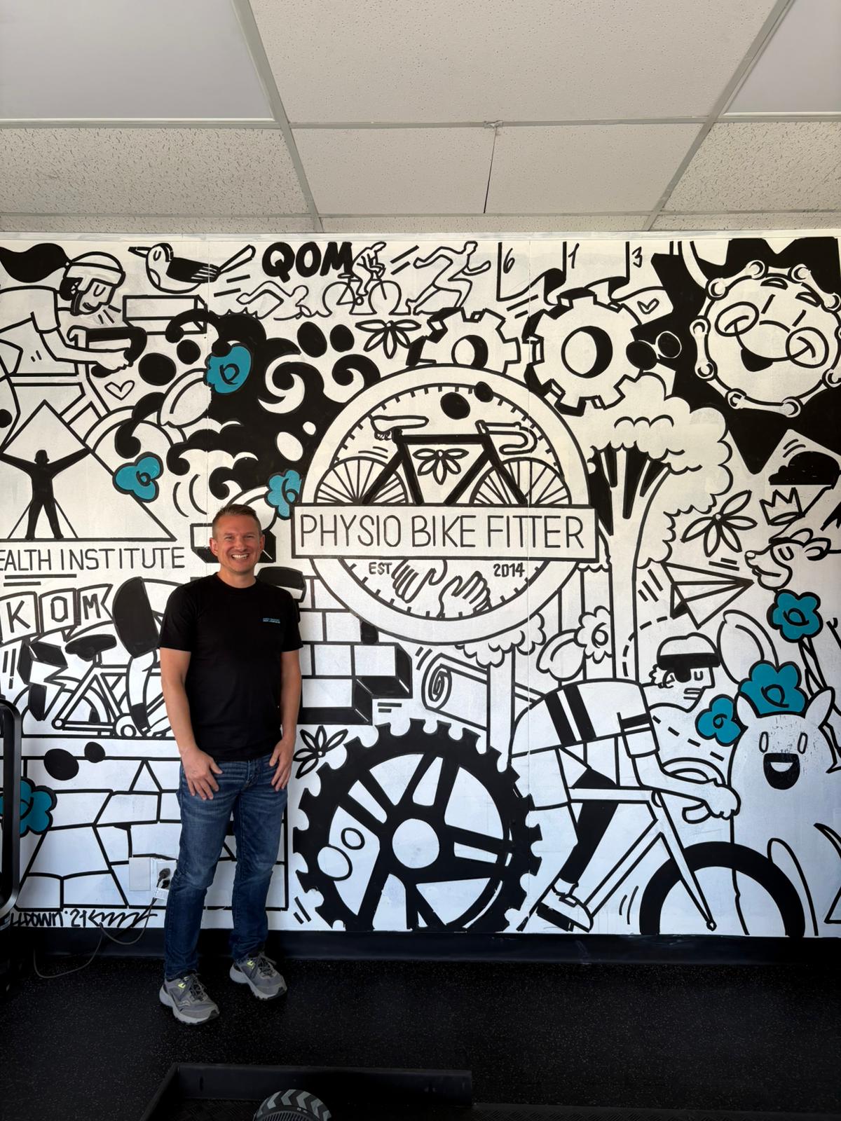 Andy Brooke standing in front of the Physio Bike Fitter mural in Ottawa