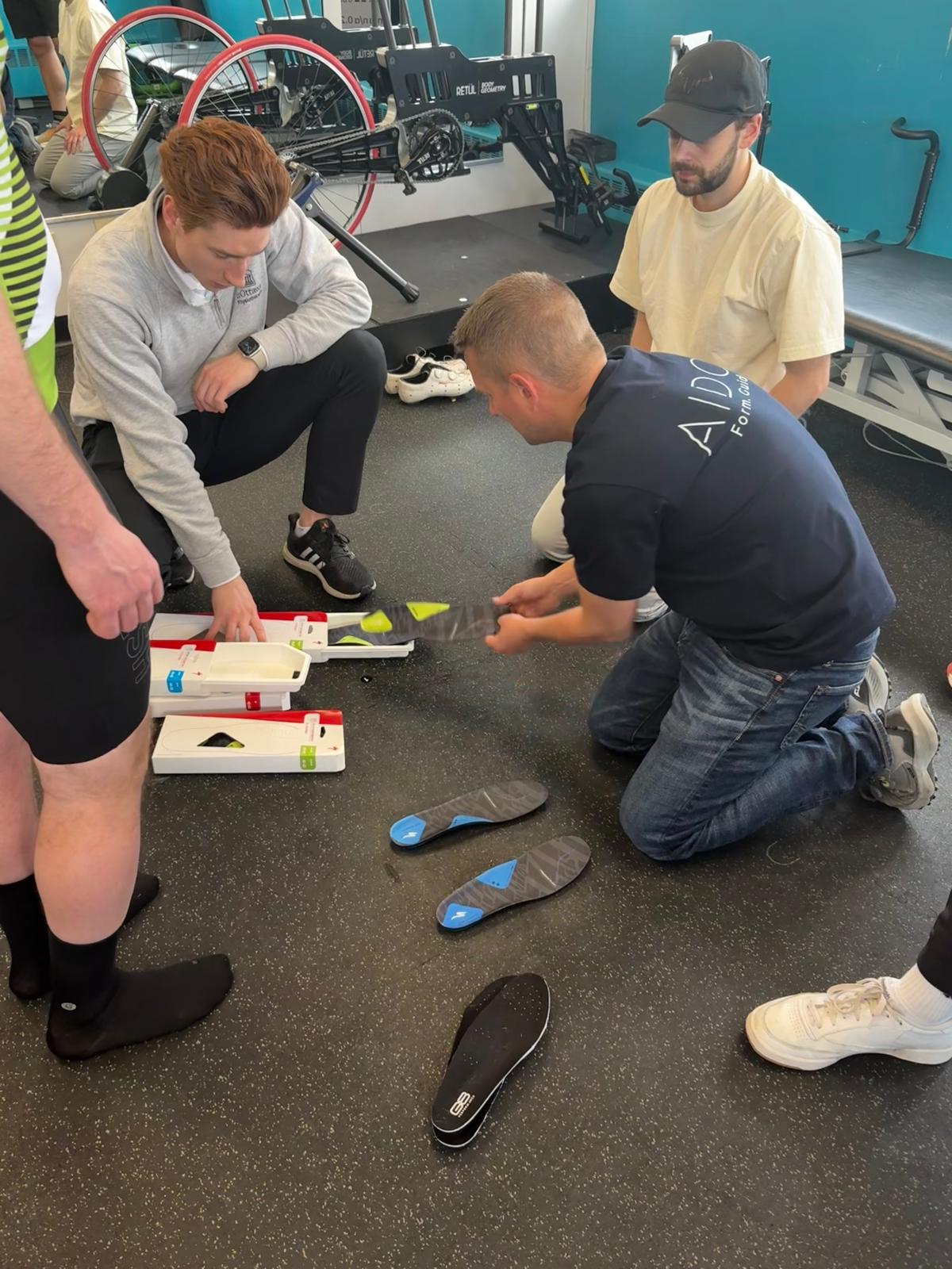 Attendees kneeling on the studio floor examining insoles and footbeds during a practical session