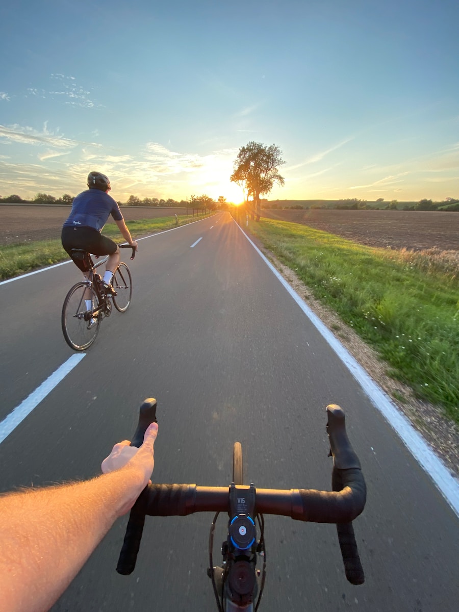 First-person view of a cyclist following another rider on a sunlit road
