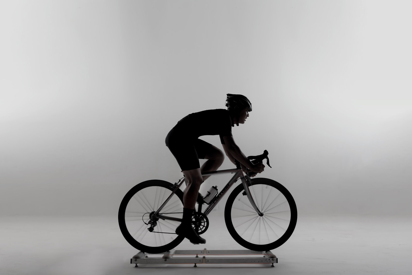 Silhouetted cyclist on a trainer against a clean studio backdrop